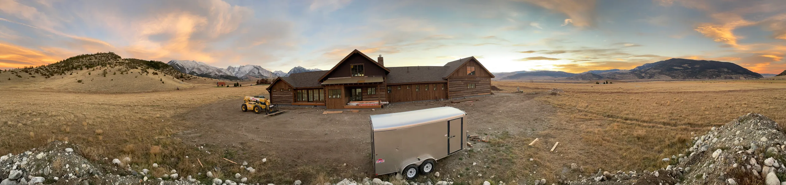 Custom log home in a mountain valley at sunset